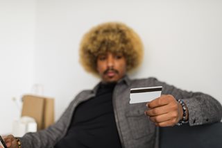 black man with afro holding a credit card