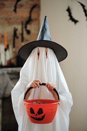 kid in a ghost costume holding a candy bucket pumpkin