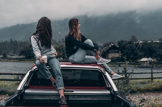 two women on top of car