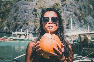 woman drinking out of coconut