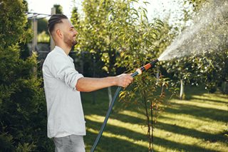 man with a hose watering a lawn