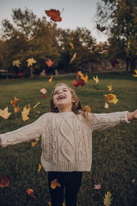 young girl throwing leaves in the air