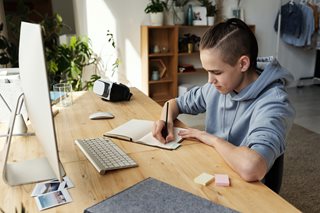 teenage boy writing in a notebook