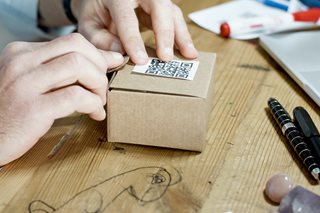 person putting a QR code on a box