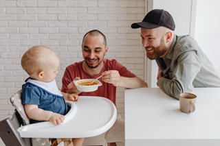 Two fathers feeding a baby