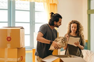 man and woman packing boxes and looking at papers