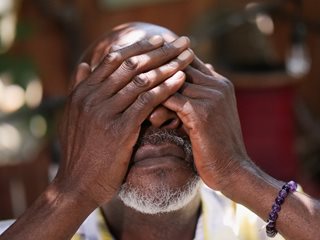 black man covering his face in shame