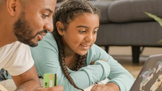 man and daughter looking at laptop holding credit card