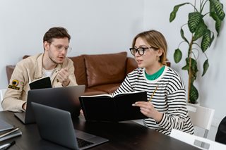 man and woman planning using laptops and notebooks