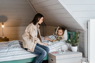 kid sick in bed with mom watching