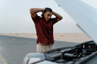 man looking at car engine with hood up