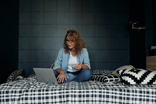 woman sitting on bed looking at laptop