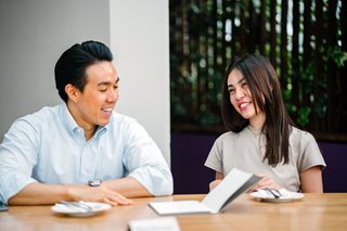 man and woman talking at a table with a notebook