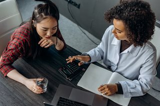 two women working on a budget with a calculator