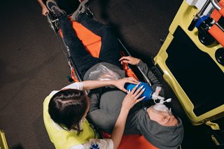 man on stretcher with breathing tool on face