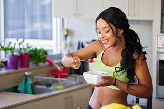 young black woman eating fruit from a bowl