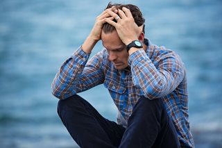 man sad sitting next to water