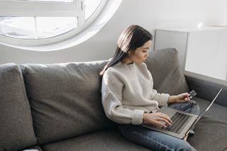woman on couch with laptop and credit card
