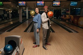 two people holding bowling balls