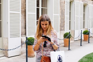 woman looking at phone holding a shopping bag