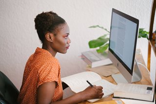 woman taking notes and looking at computer