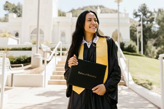 woman in graduation gown holding a diploma