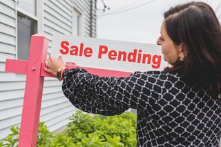 woman hanging a Sale Pending sign