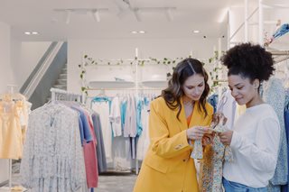 teenager girl and sales person looking at price tag of dress