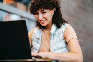 woman with curly hair looking at laptop