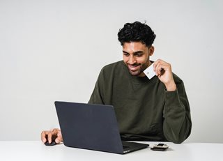 man with credit card looking at laptop