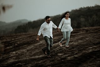 man and woman walking in a forest holding hands