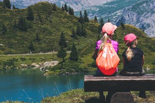 two girls sitting on bench next to lake