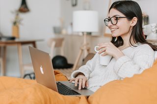 woman holding a mug looking at a laptop