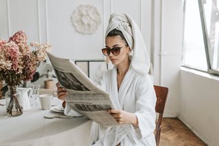 woman in robe looking at newspaper
