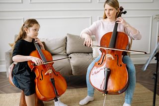 woman and young girl playing cello