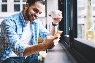 man with coffee looking at cellphone
