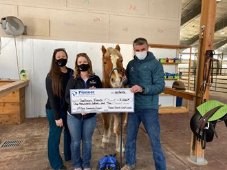 three people and a horse holding a giant check