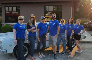 group of team members standing in front of old car