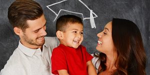 Parents holding son with chalk graduation hat in background over kids head